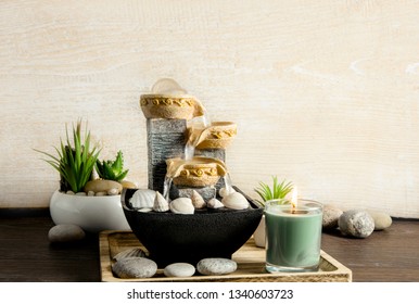 Portable Indoor Fountain For Good Feng Shui In Home Or Office. Small Indoor Tabletop Fountain With Water Flowing. Spiritual Mind And Soul Balance Concept. Green Plants In Flower Pot On Background.