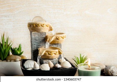 Portable Indoor Fountain For Good Feng Shui In Home Or Office. Small Indoor Tabletop Fountain With Water Flowing. Spiritual Mind And Soul Balance Concept. Green Plants In Flower Pot On Background.