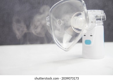 
Portable Inhaler, White Nebulizer On A Table.