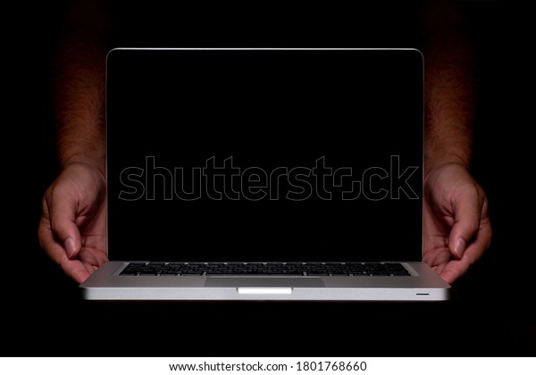 Portable modern silver computer on a black\
background. Computer in male hands.\
