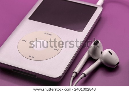 portable mp3 player with white headphones on a solid pink background (isolated, close up, macro) nostalgia for 90's and 2000's