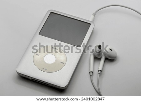 portable mp3 player with white headphones on a solid white background (isolated, close up, macro) nostalgia for 90's and 2000's