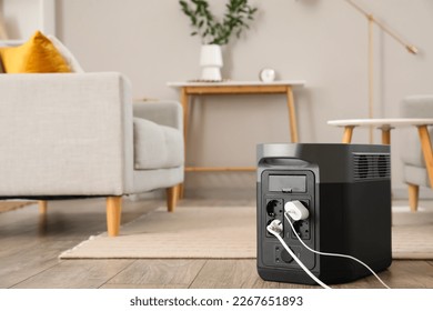 Portable power station charging devices on floor in living room - Shutterstock ID 2267651893