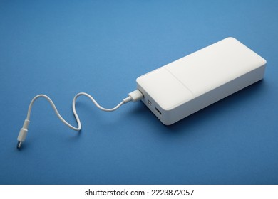 Portable powerbank with usb cable on blue background. Top view