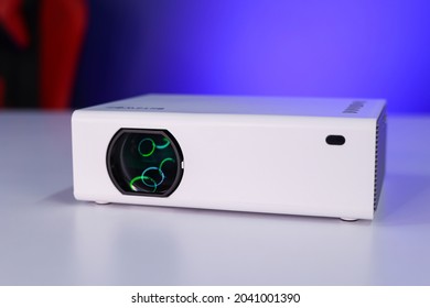 A Portable Projector On A White Table In A Studio, Green Ring Light Reflecting On Lens. This Is A Chinese Projector Used To Watch Movies And Office Work.