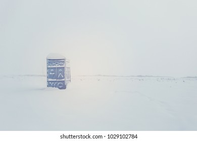 A Portable Restroom Site In A Empty Snow Covered Field.