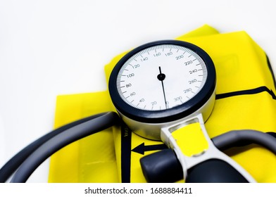 A Portable Sphygmomanometer Resting On A Yellow Cuff For Adults. Instrument For Measuring Blood Pressure. Graduated Scale With Pressure Indicator. Medical Device. Health And Disease Prevention