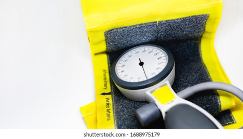 A Portable Sphygmomanometer Resting On A Yellow Cuff For Adults With A Velcro Closure. Instrument For Measuring Blood Pressure. Graduated Scale With Pressure Indicator. Medical Instrument. 