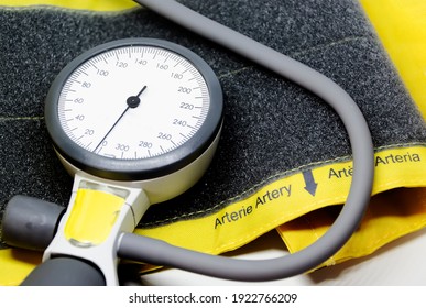 A Portable Sphygmomanometer Resting On A Yellow Cuff For Adults With Velcro Closure. Instrument For Measuring Blood Pressure. Graduated Scale With Pressure Indicator. Medical Instrument. 