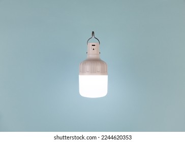 Portable USB rechargeable LED emergency light with built-in battery on blue a background. Light source during blackout. Minimalistic composition. - Shutterstock ID 2244620353