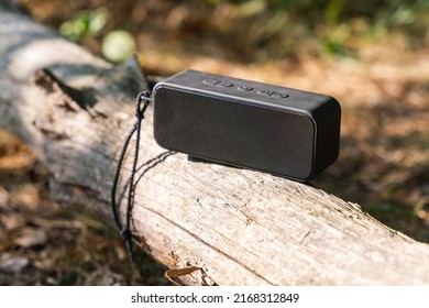 Portable Wireless Speaker For Listening To Music On A Log In The Forest.
