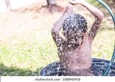 Portail Of A Cute Boy Enjoing Shower In The Black Basin Outside The House And Spray Water Over His Head.