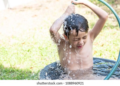 Portail Of A Cute Boy Enjoing Shower In The Black Basin Outside The House And Spray Water Over His Head.