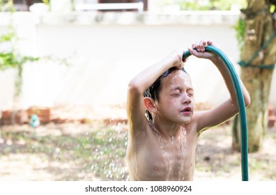 Portail Of A Cute Boy Enjoing Shower In The Black Basin Outside The House And Spray Water Over His Head.