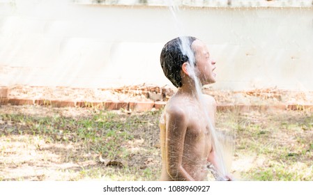 Portail Of A Cute Boy Enjoing Shower In The Black Basin Outside The House And Spray Water Over His Head.