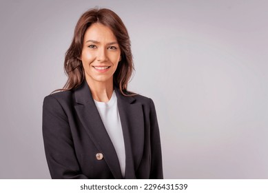 Portait of an attractive businesswoman wearing black blazer and standing at isolated background. Copy space.