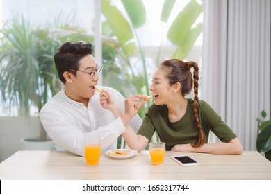 Portait of beautiful family happy man and woman having breakfast in house while sitting at table 