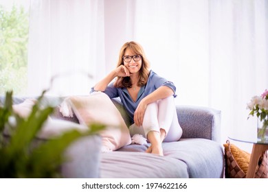 Portait Of A Beautiful And Happy Mature Woman Relaxing On A Sofa At Home. 