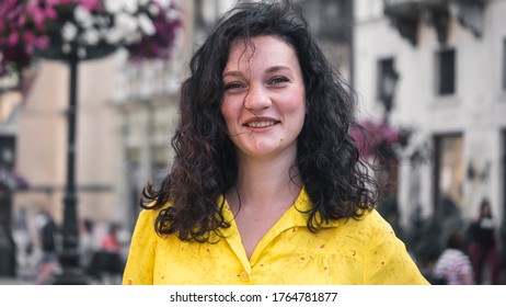 Portait of Beautiful Young Lady Wearing Yellow Dress Curly Hair Looking Happy. Young Attractive  woman smiling happy and confident. Standing at town street.