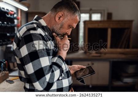 Portait of carpenter in his workshop using tablet.