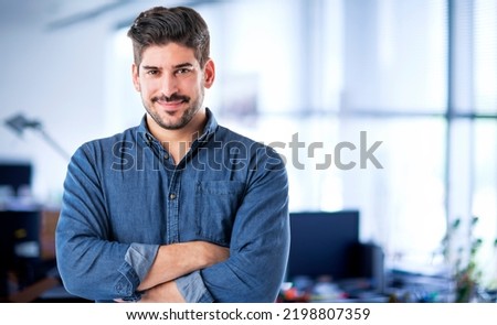 Portait of handsome businessman standing with arms crossed at the office. Copy space. He is smiling.