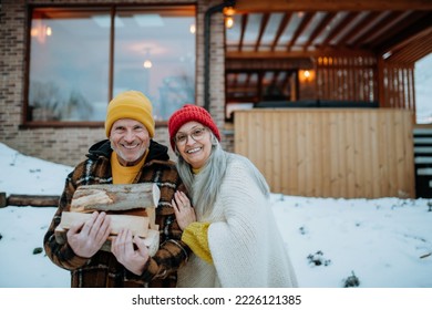 Portait of senior couple carrying wooden logs and preparing outdoor fire, during winter day. - Powered by Shutterstock