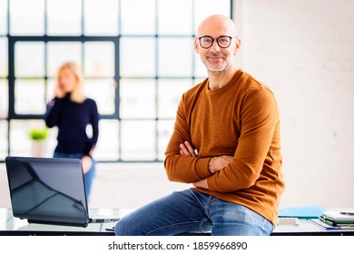 Portait shot of senior businessman wearing casual clothes while sitting at desk in the office.