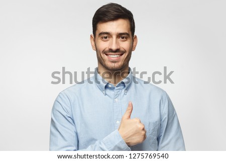 Portait of smiling businessman with thumbs up gesture, isolated on gray background 
