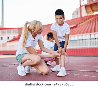 Portait of sports coach, children at stadium having althletics training. Portrait of a little boy having an injury during a traing helped and supported by the coach - Powered by Shutterstock