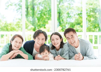 portait of a three generation asian family looking at the camera lying together on the bed.