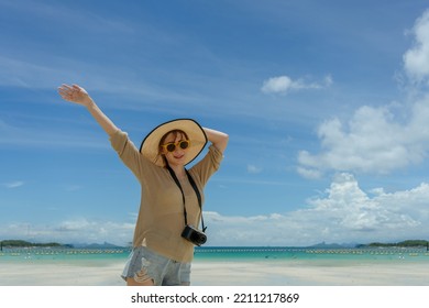 portait of woman wearing sun hat sungrasses and have camera standing on the beach with sunny day