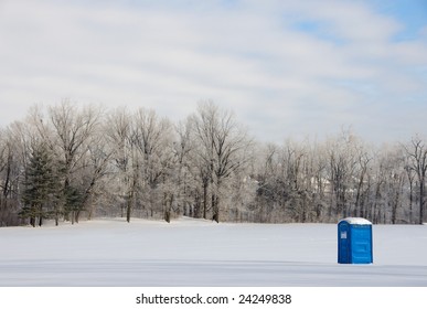 A Port-a-potty Sits In A Remote Field Covered In Snow