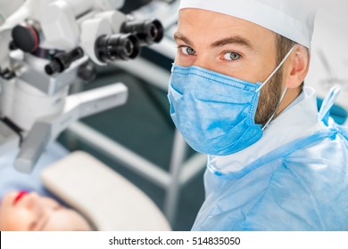 Portarit of eye surgeon at the working plase near the microscope in the operating room