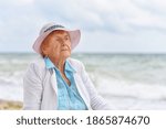 Porter of a very old 84-year-old brooding woman sitting on the seashore.