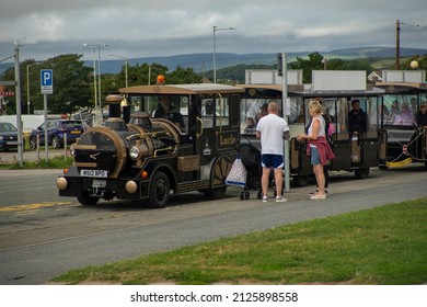 Porthcawl, Wales, UK - 08.19.2021: A Queue Of People Are Getting On A Pretend Steam Train At Porthcawl Beach. This Steam Train Travels On Roads Instead Of Railway Tracks.