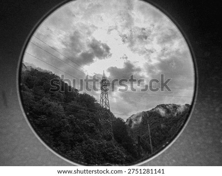 Porthole Framing Tower Under Dramatic Clouds. Blackandwhite Hillside Valley With Silhouetted Pylon, Dense