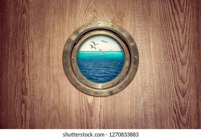 Porthole window on ship board with a seascape - view on the ocean and flying birds over tropical island. Brass porthole frame at the old sailing vessel for your marine design with place for text.