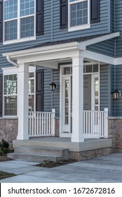 Portico leading to the entrance of vinyl horizontal lap siding covered building, with a roof structure over the entryway, supported by white rectangular columns on a new single family home in Maryland