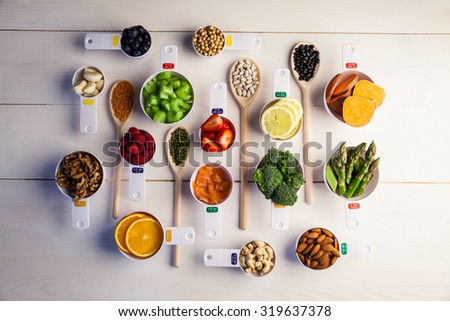 Portion cups and spoons of healthy ingredients on wooden table