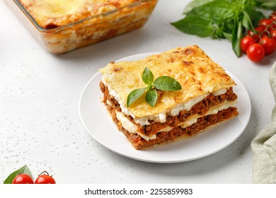 Portion of Homemade Italian lasagna. Delicious Lasagne with bolognese meat sauce and basil on white plate. Hot Tasty Lasagna with cheese.
