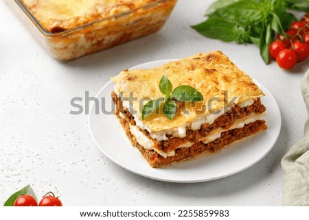 Portion of Homemade Italian lasagna. Delicious Lasagne with bolognese meat sauce and basil on white plate. Hot Tasty Lasagna with cheese.