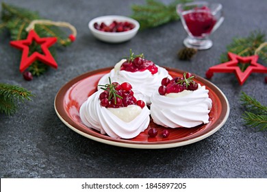 Portion Pavlova Meringue Pastries With Cream And Cranberry Sauce In New Year's Or Christmas Decor On A Red Plate On A Dark Concrete Background. New Year And Christmas Desserts. Meringue Recipes