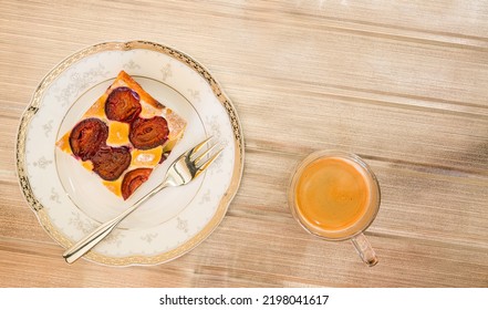 Portion Of Plum Cake On A Porcelain Plate With A Fork. A Cup Of Espresso. View From Above.