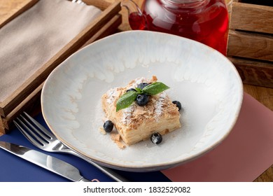 A Portion Of Puff Pastry Napoleon Cake In A Wide Restaurant Dish, Top View