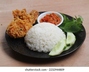 a portion of rice with a side dish of Kentucky fried chicken with vegetables and spicy chili sauce. nasi, ayam goreng, lalapan and sambal