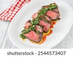 Portion of sliced strip steak with Chimichurri sauce