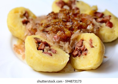 Portion of the sliced traditional czech potato dumplings stuffed with smoked meat, braised cabbage and fried onion.