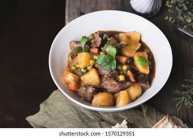 Portion of traditional irish beef and guinness beer stew with carrots, potatoes and green peas