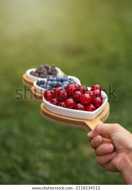 Portion wooden dish on green background top
view,in a hand on the grass. Wooden partitioned dish divided into
equal 3 section. Compartmentals dish for food, dessert, fruit,
berries and vegetable.