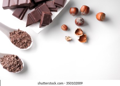 Portions and chocolate chips with hazelnuts on a white porcelain container on a white wooden table isolated. Horizontal composition. Top view - Shutterstock ID 350102009
